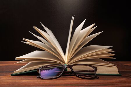 Open book with glasses on black  background. - Image