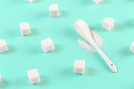 background of sugar cubes and sugar in spoon. White sugar on turquoise background. Sugar with copy space. Top view or flat layの写真素材