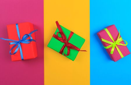 Different colored gift box on color background. Top view of various present boxes on minimal...