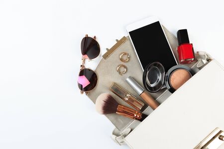 Fashion concept : Flat lay of white  leather woman bag open out with sunglasses and smartphone on white background.の写真素材