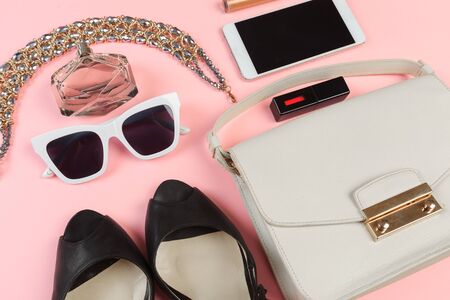 Top view of Women bag and lady stuff with copyspace on pink background