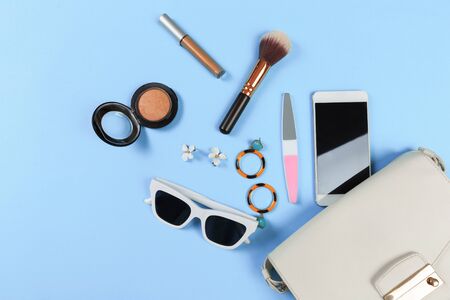 Top view of Women bag and lady stuff with copyspace on blue  background