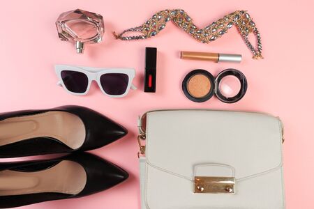 Top view of Women bag and lady stuff with copyspace on pink background