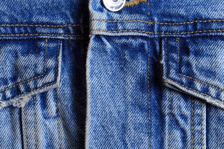Dark blue jeans texture for design. Part of the cyan jeans jacket with pocket and a metallic button...