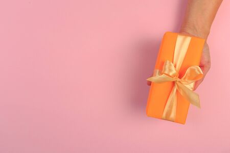 gift in female hands on a colored background top view.の写真素材