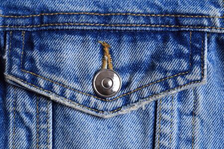 Dark blue jeans texture for design. Part of the cyan jeans jacket with pocket and a metallic button...