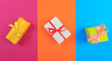 Different colored gift box on color background. Top view of various present boxes on minimal...