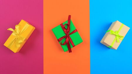 Different colored gift box on color background. Top view of various present boxes on minimal...