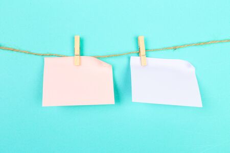 a piece of white paper attached to a rope clothespin on blue  background