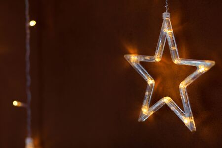 Christmas lights in the shape of a star . Yellow shiny illumination, Christmas decor, copy space.の写真素材