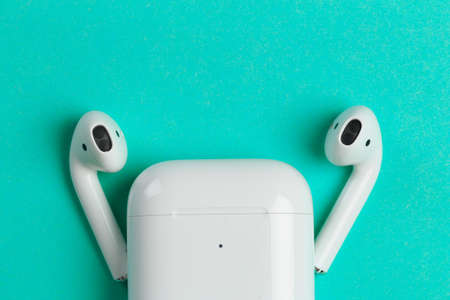 New wireless headphones in the charging box, blue  background. air pods convenient contactless headphones, stylish bright backgroundのeditorial素材