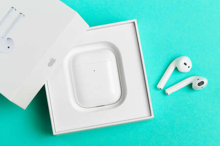 New wireless headphones in the charging box, blue  background. air pods convenient contactless...