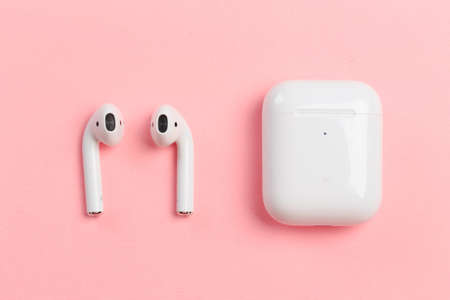 White headphones with box case on pink background. Modern technology pods with air connection....