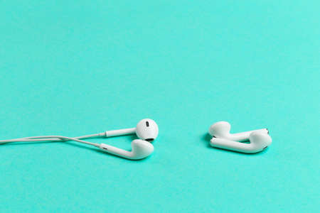 Comparison of two tipes of headphones on blue background. Modern technology pods vs obsolete headphones. Wireless earphones device. New way to leasten music. Concept of free choice.のeditorial素材