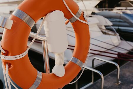 lifebuoy hanging on metal railing, on the background of marina. Sea shore, sunny day, outdoor.
