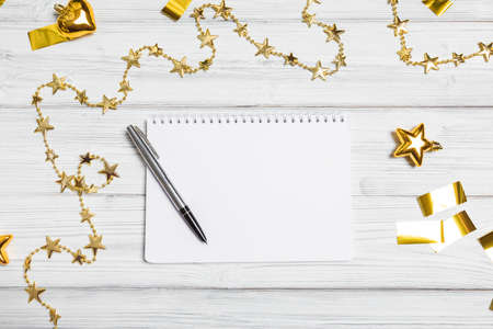 golden christmas decorations and notebook on white background. Flat lay, top view, copy spaceの写真素材