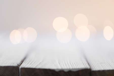 white abstract bokeh background behind wooden deskの写真素材
