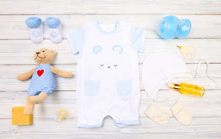 baby boy clothes and  attributes on a white wooden background. View from above