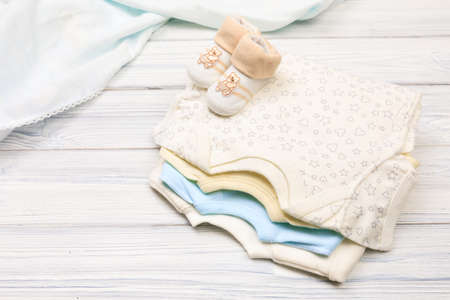 baby clothes and  attributes on a white wooden background. View from above