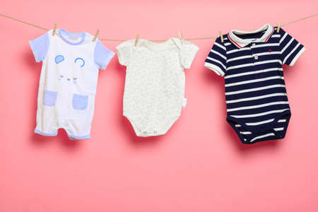 Baby clothes on a clothesline on pink background - Imageの写真素材