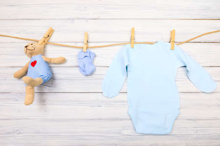 Baby clothes and  toy bear on a clothesline on wooden backgroundの写真素材