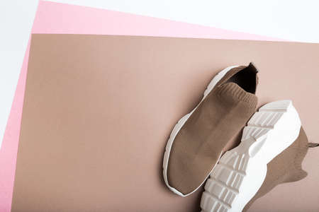 modern beige sneakers with white soles on beige background