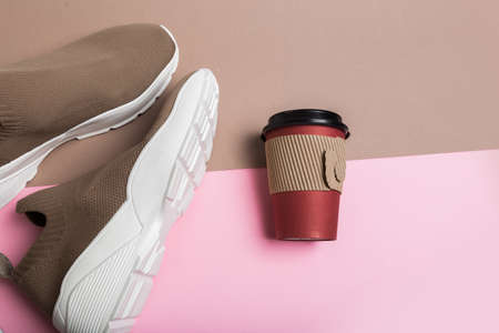modern beige sneakers and a cup of coffee on multicolour backgroundの写真素材