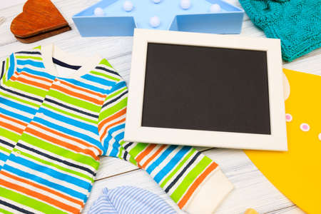 baby clothes and  attributes on a white wooden background. View from above