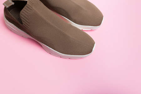 modern beige sneakers with white soles on pink background