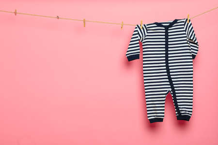 Baby clothes on a clothesline on pink background - Image