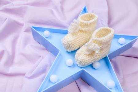 crumpled fabric lilac fleece background  with star shaped night light and baby booties