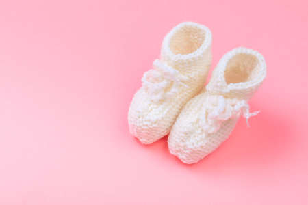 knitted baby booties on pastel pink background - Imageの写真素材