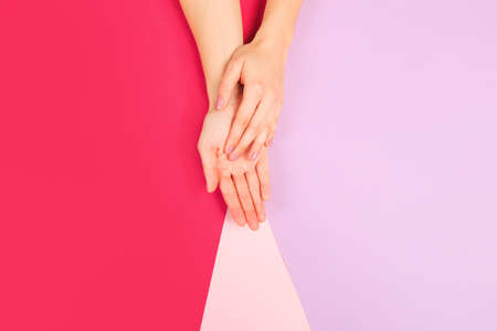 female  manicure. Beautiful young woman's hands on color pink  backgroundの写真素材
