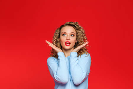 beautiful young woman in blue blouse and  with curl hair posing on red background - Image