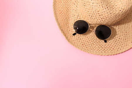 round shape black sunglasses with summer hat  on pink background with tropical leaf shadowの写真素材