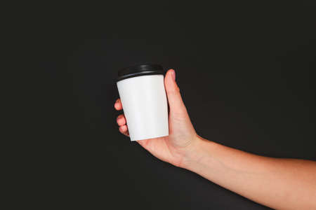 female  manicure. Beautiful young woman's hands holding coffee on black backgroundの写真素材