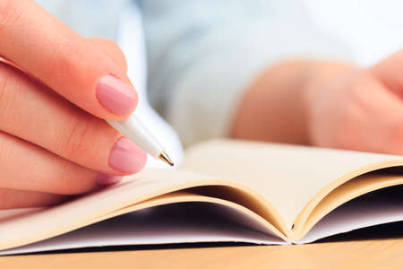 female hands write in a notebook . Office place . Close up viewの写真素材