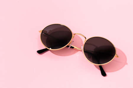 round shape black sunglasses on pink background with tropical leaf shadowの写真素材