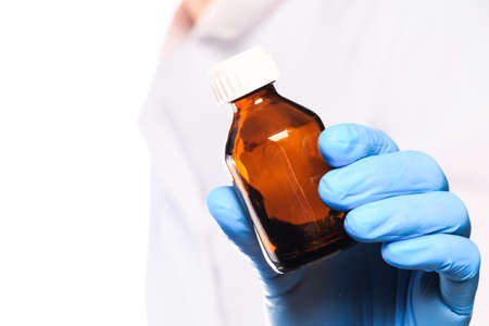 Doctor hand in sterile gloves holding glass vial isolated on white backgroundの写真素材