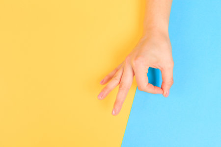female  manicure. Beautiful young woman's hands in OK sign on pastel color  backgroundの写真素材