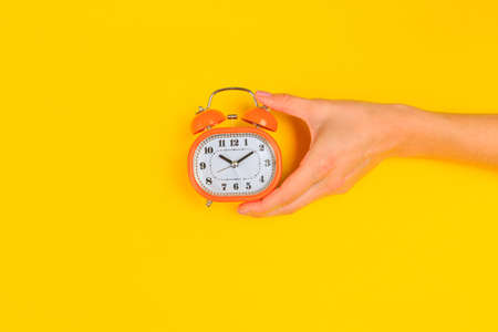 Beautiful young woman's hands with alarm clock  on pastel  background - Imageの写真素材