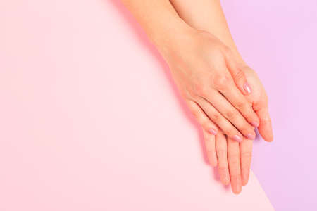 female  manicure. Beautiful young woman's hands on pastel pink  backgroundの写真素材