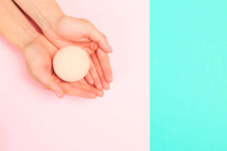 female  manicure. Beautiful young woman's hands holding a bathroom bomb on pastel background - Imageの写真素材