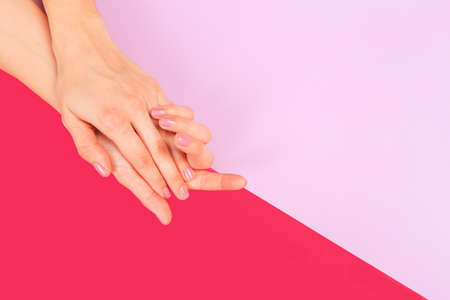 female  manicure. Beautiful young woman's hands on color pink  backgroundの写真素材