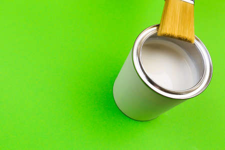 hand holding Brush  on open can of paint on green  background. Renovation conceptの写真素材