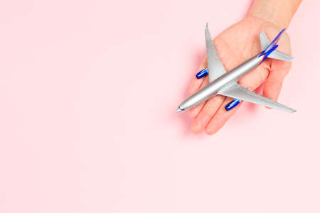 Beautiful young woman's hands holding plane    on pastel  background - Imageの写真素材