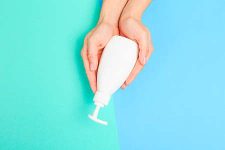 Beautiful young woman's hands with  white care bottle   on pastel background - Imageの写真素材