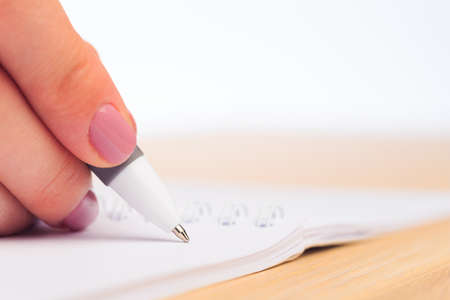 female hands write in a notebook . Office place . Close up view