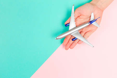 Beautiful young woman's hands holding plane    on pastel  background - Imageの写真素材