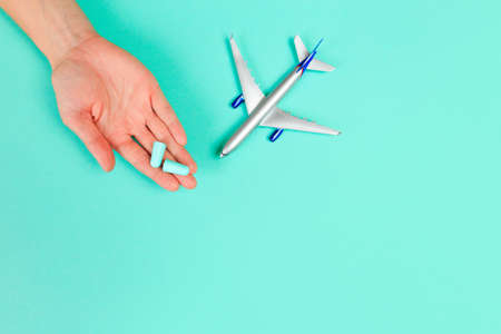 Beautiful young woman's hands holding plane and ear plugs  on pastel  background - Imageの写真素材